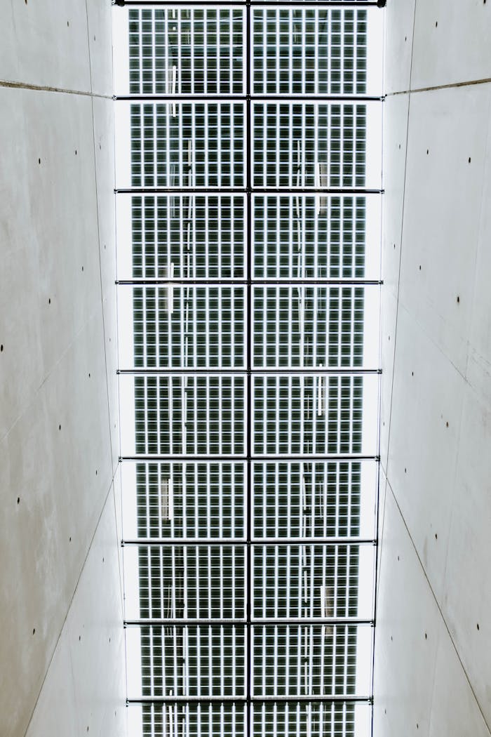 about-04 Abstract view of a modern ceiling with glass panels and metal grills in a hallway.